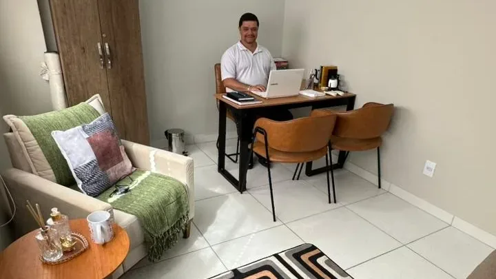 Wagner Washington na sala de atendimento da WD NeuroClínica Integrada, com poltrona, tapete e mesa de trabalho